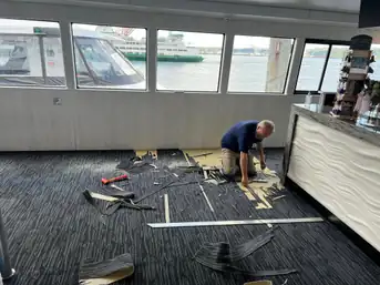 A wide shot of the Argosy boat job, cut carpet remnants and tools on the floor, ferry visible through the windows