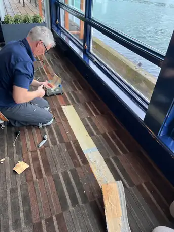 A technician cutting seam tape beside a window overlooking the water