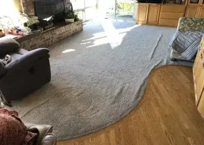 A living room carpet buckled into a long wave in front of the fireplace