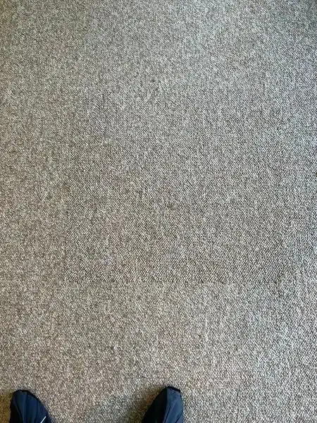 A close top-down view of a finished carpet patch with the seam barely visible