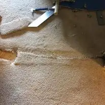 A close-up of a carpet seam that has separated and started to fray