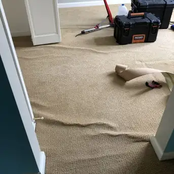 A room of carpet visibly loose and rippled before stretching